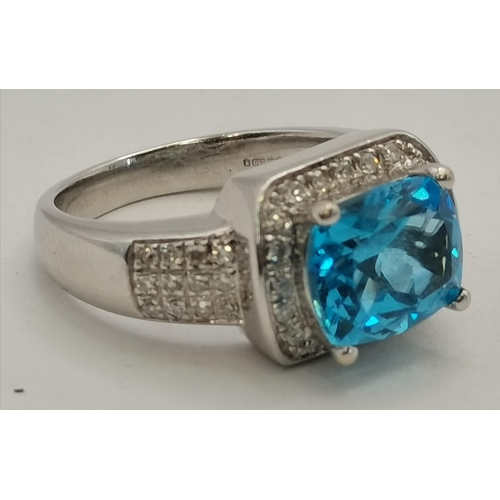 392 - An 18 carat white gold topaz and diamond ring, the cushion-cut topaz in a claw setting above a surro... 