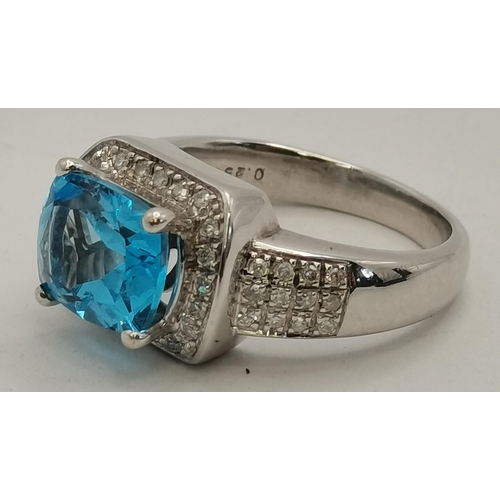 392 - An 18 carat white gold topaz and diamond ring, the cushion-cut topaz in a claw setting above a surro... 