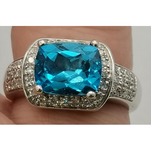 392 - An 18 carat white gold topaz and diamond ring, the cushion-cut topaz in a claw setting above a surro... 