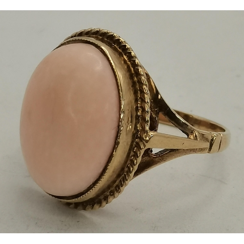 397B - A 9 carat gold pink hardstone ring, the large oval cabochon set with a rope-twist border to a raised... 