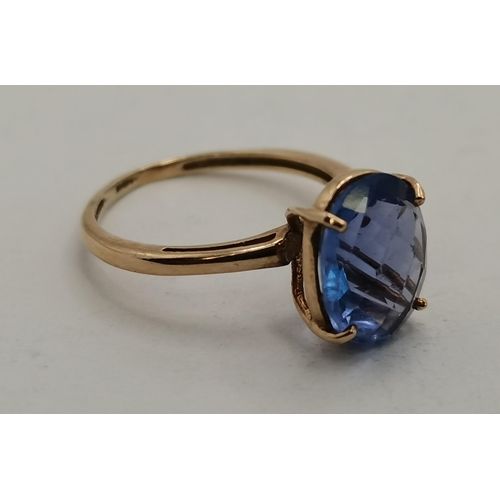 397C - A 9 carat gold blue stone dress ring, the oval stone in a raised and pierced claw setting, the shank... 