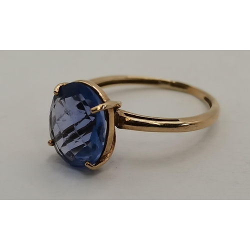 397C - A 9 carat gold blue stone dress ring, the oval stone in a raised and pierced claw setting, the shank... 