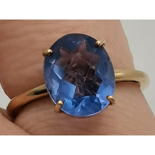 397C - A 9 carat gold blue stone dress ring, the oval stone in a raised and pierced claw setting, the shank... 