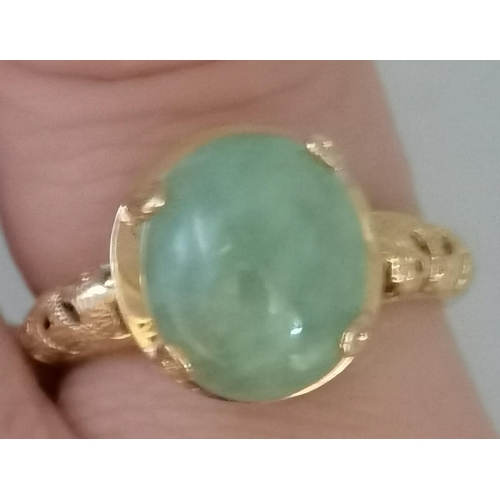 397D - A 14 carat gold jade ring, the loose oval cabochon stone to an open-backed claw setting, the mount a... 