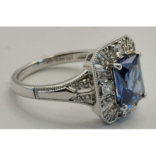 406B - A silver and cubic zirconia rectangular halo ring, the central rectangular blue stone enclosed by a ... 