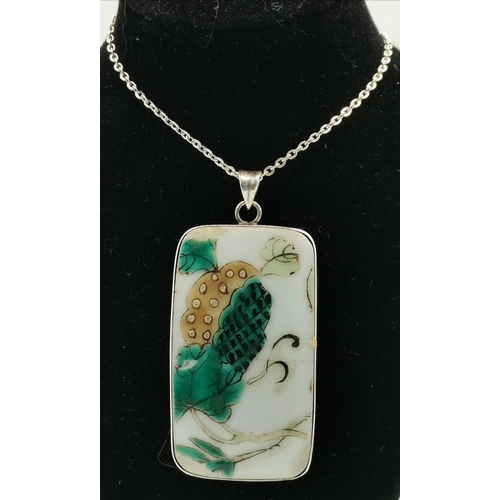 449 - A silver-mounted Chinese porcelain plaque pendant necklace, the slightly curved rectangular famille ... 