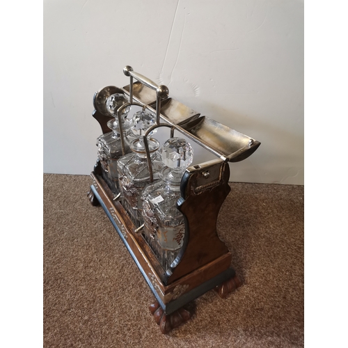 5 - A large walnut tantalus with white metal fixings and cover, enclosing three square cut-glass decante... 