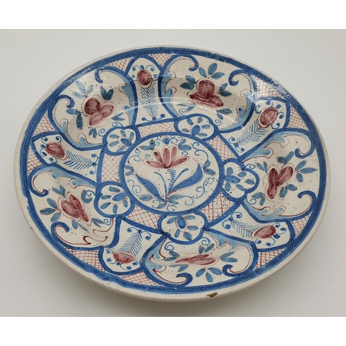 133 - A Continental large faïence pottery dish, decorated in scrolling tonal blues with maroon lattice det... 