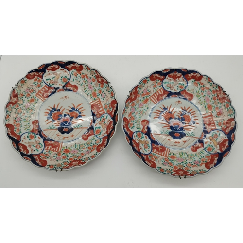 143 - A collection of five Japanese Imari wall chargers and plates, comprising a large pair of chargers, a... 