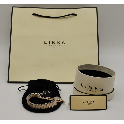 400 - A friendship bracelet by Links of London, the vertical cylinders bound by cream cord, with black clo... 