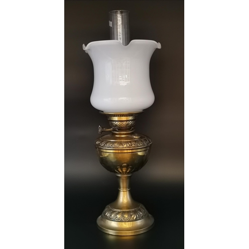 10 - A Victorian brass oil lamp with clear glass chimney and white tulip shade. 53.5cm high overall