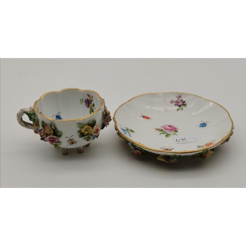 161 - A Meissen floral-encrusted footed teacup and saucer, with underglaze blue crossed swords marks to ba... 