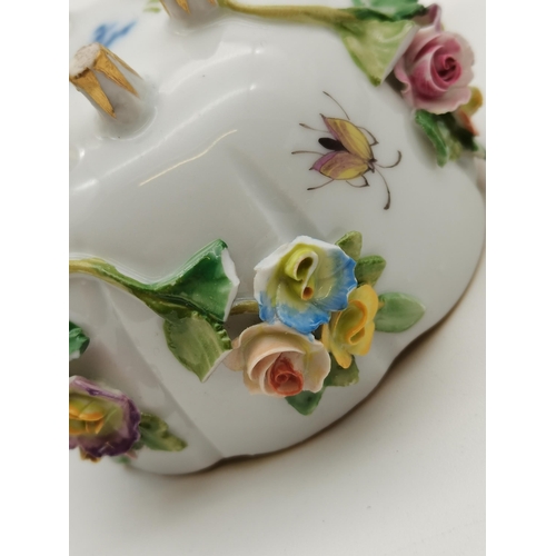 161 - A Meissen floral-encrusted footed teacup and saucer, with underglaze blue crossed swords marks to ba... 