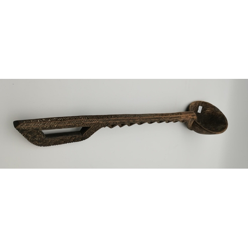 25 - An Indian carved wooden ladle, with D-shaped handle. 59.5cm long