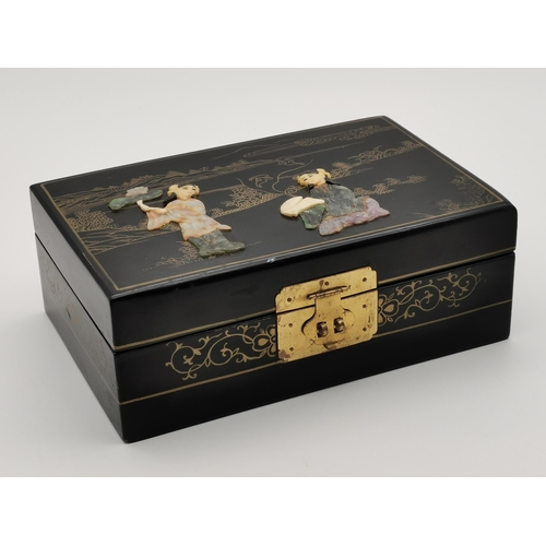 79 - An oriental lacquered jewellery box, rectangular, with gilt decoration, the cover inlaid with hardst... 