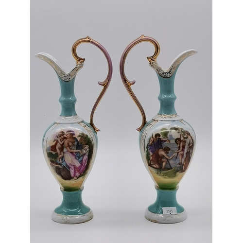 203 - A pair of Von Schierholz porcelain 30cm ewers with Greek style God figure decoration