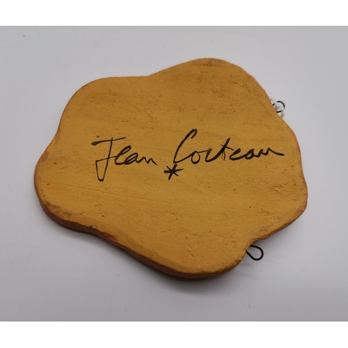 503 - Jean Cocteau (French, 1889-1963), A freeform terracotta pendant of a face in profile, the naturalist... 