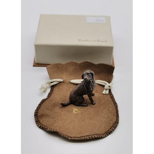 511 - A miniature bronze labrador figure by Butler and Peach, with soft pouch and box. 3.5cm high