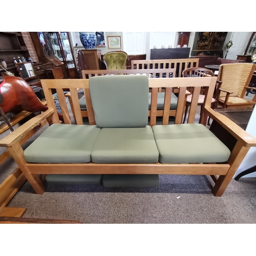 662 - A 'Thistleman' oak three-seater bench settee, with removable green fabric loose cushions, with reces... 