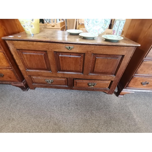 703 - A Georgian oak mule chest, the three-panelled front with hinged cover, over two drawers with brass s... 