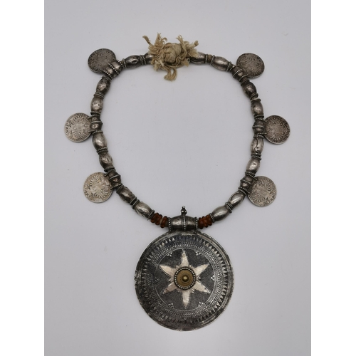 437 - Omani silver: A Samt Mukhahal white metal necklace, the large central disc with gilt sunburst design... 