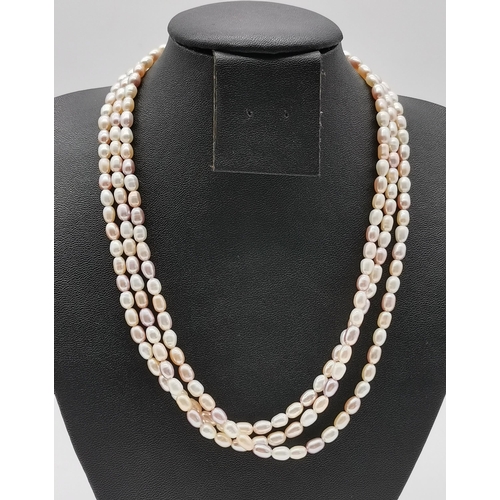 498 - A triple strand pearl necklace in hues of pink; together with two simulated pearl necklaces, one by ... 