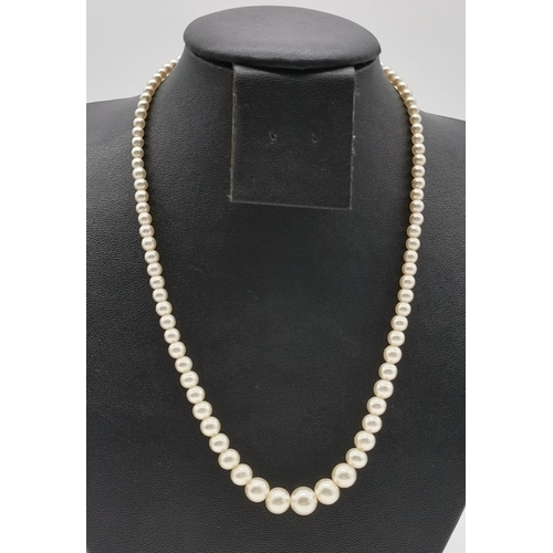 498 - A triple strand pearl necklace in hues of pink; together with two simulated pearl necklaces, one by ... 