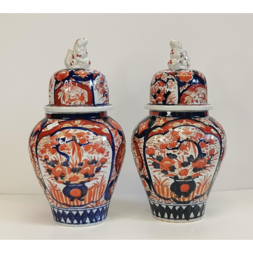 30 - A Pair of Imari Ribben Vases with Foo Dog Lids decorated with shield shapes enclosing floral designs... 