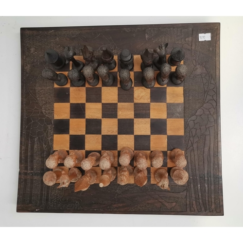 47 - An African wooden chess set, the broad board edge carved with figures and giraffes, the playing piec... 