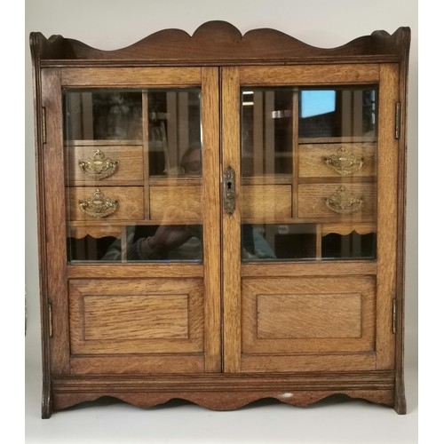 64 - An oak smoker's cabinet, early-mid 20th Century, the two part-glazed doors revealing a fitted interi... 