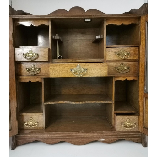 64 - An oak smoker's cabinet, early-mid 20th Century, the two part-glazed doors revealing a fitted interi... 