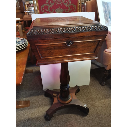 723 - An early Victorian rosewood teapoy, the sarcophagus form caddy with hinged cover carved with a band ... 