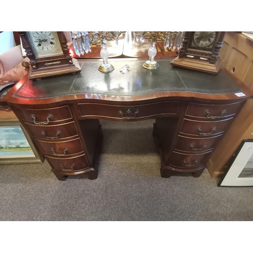 725 - A reproduction mahogany serpentine kneehole desk, the shaped top with gilt-tooled green leather writ... 