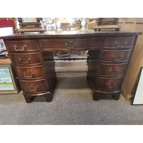 725 - A reproduction mahogany serpentine kneehole desk, the shaped top with gilt-tooled green leather writ... 