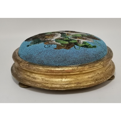 13 - A Victorian beaded footstool, circular, decorated with flowers and foliage to a blue ground, to a gi... 