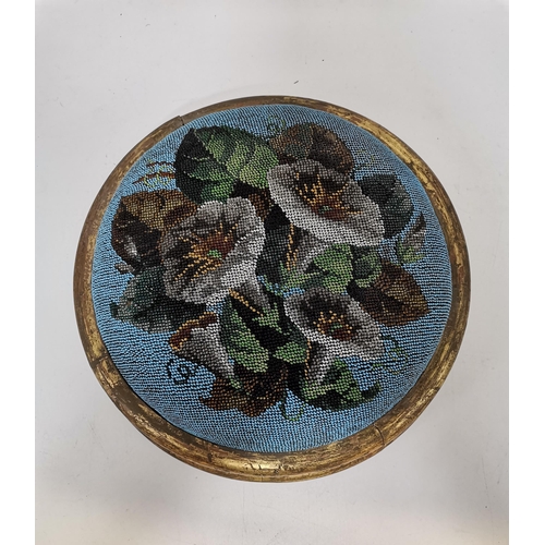 13 - A Victorian beaded footstool, circular, decorated with flowers and foliage to a blue ground, to a gi... 