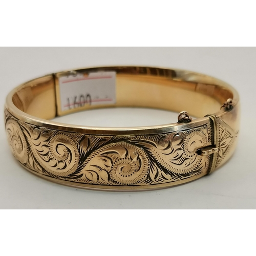 444 - A 9 carat gold hinge-opening bangle, engraved to front with scrolling foliate decoration, stamped 9C... 