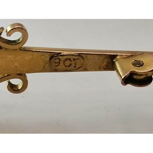 446 - A 9 carat gold gem-set bar brooch, the central oval pink stone enclosed within s-scroll supports, st... 