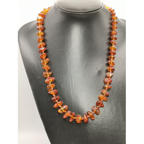 449A - A string of amber beads, graduated naturalistic shapes, largest approx. 18mm by 8mm, triangular. 59c... 
