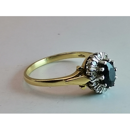 527A - An 18 carat gold blue and white stone cluster ring, the central oval stone enclosed by ten small rou... 