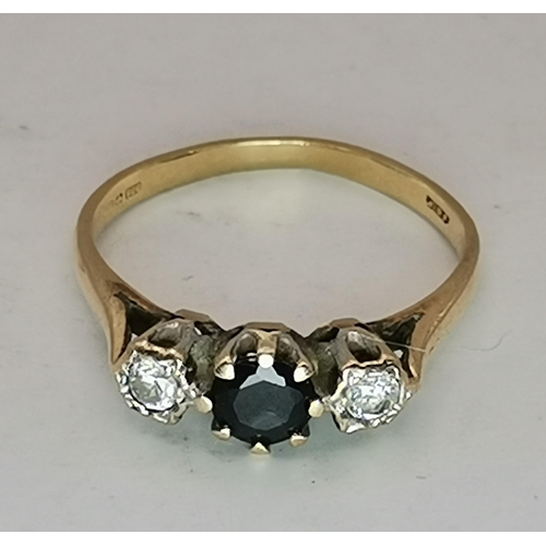 528 - A 9 carat gold three stone ring, the central blue round stone flanked by two round white stones, cla... 