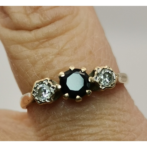 528 - A 9 carat gold three stone ring, the central blue round stone flanked by two round white stones, cla... 