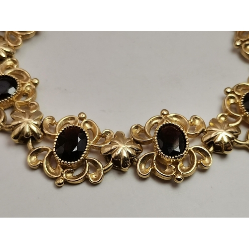 529A - A 9 carat gold and eight stone garnet fancy link bracelet, the oval stones set to ornate scrolling l... 