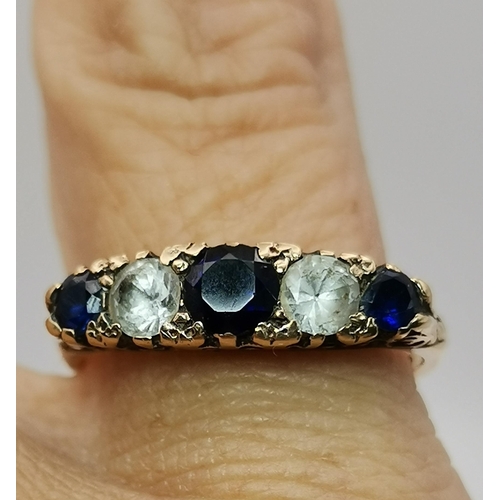 548A - A 9 carat gold five stone ring, with three graduated round blue stones spaced by two round white sto... 
