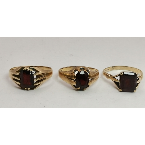 559A - Three 9 carat gold garnet solitaire rings, each with a claw-mounted stone, two rectangular and one o... 