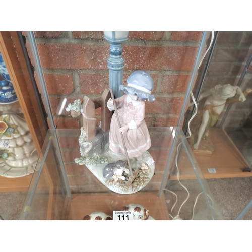 111 - A Lladro figure group, Girl sweeping leaves with cat beneath a street lamp, no. 5286. 33cm high