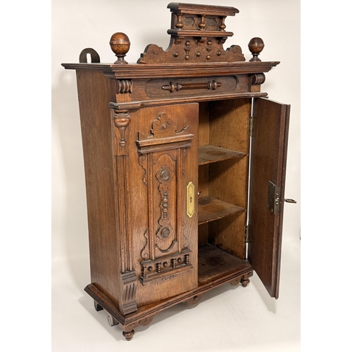 3 - An antique Continental wooden table-top cabinet, the two doors with applied carved decoration openin... 