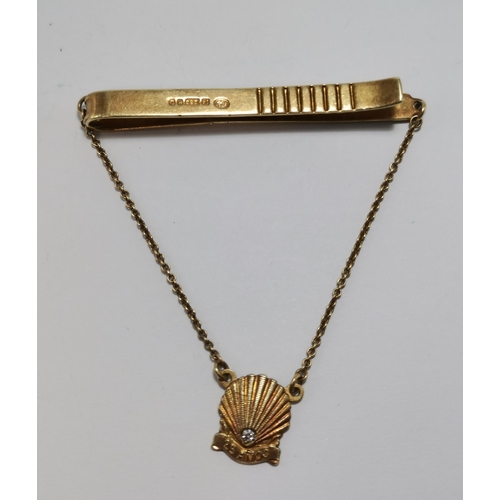 577A - A 14 carat gold tie bar and chain, suspending a scallop shell set with a diamond and '25 AÑOS', hall... 