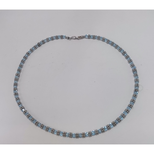 672 - An 18 carat white gold aquamarine necklace, faceted round blue stones spaced by pairs of six white-g... 