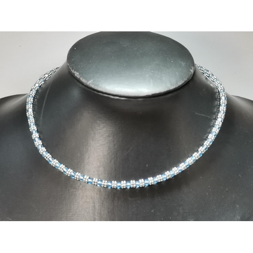672 - An 18 carat white gold aquamarine necklace, faceted round blue stones spaced by pairs of six white-g... 